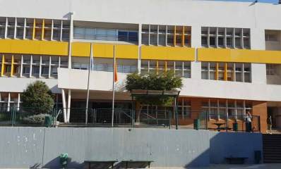 תיכון ע"ש ב. אוסטרובסקי ברעננה. תמונה מבחוץ של הבניין, בן שלוש קומות. בין קומה שתיים לשלוש פס הבטון צבוע בצהוב.