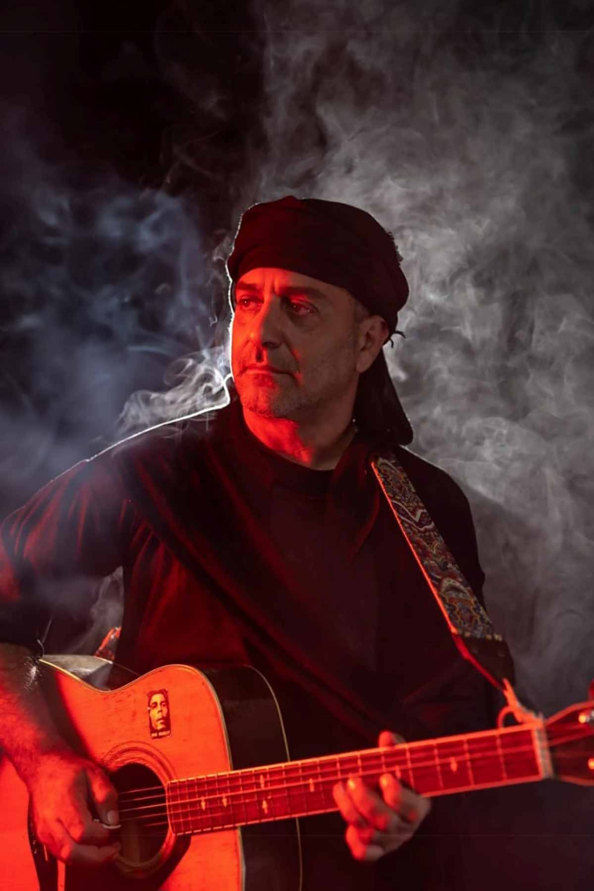 רואי לוי שוטה הנבואה עם גיטרה ומצנפת שחורה בראשו.