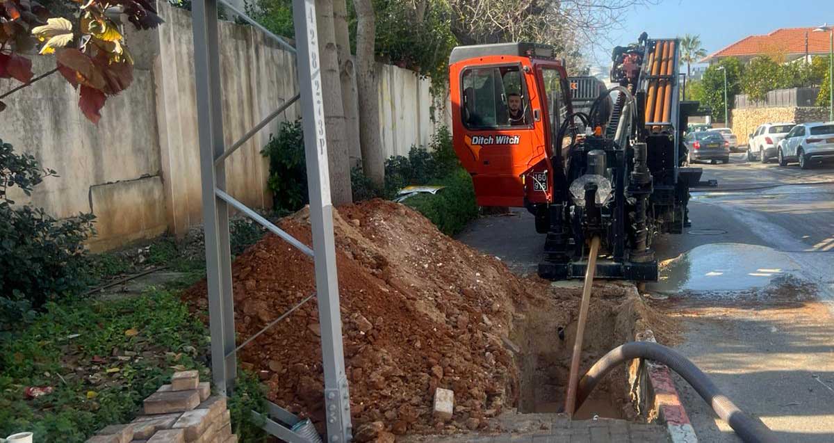 סוג של מחפרון ומניח ומניח צנרות מתחת למדרכה בפעולה