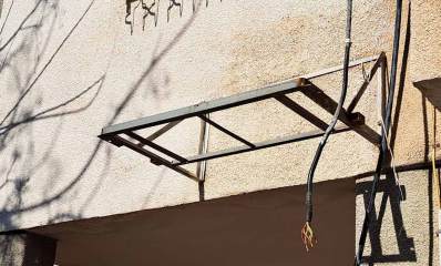 תושבת מזגן מיותמת על הקיר החיצוני של הבניין, לאחר שהמזגן נגנב, והכבלים של המזגן תלויים ליד התושבת.