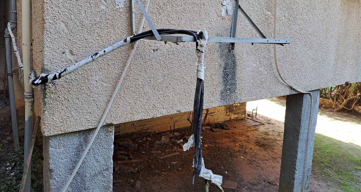 תושבת מזגן מיותמת על הקיר החיצוני של הבניין, לאחר שהמזגן נגנב, והכבלים של המזגן תלויים ליד התושבת.