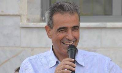 מאיר דהן תמונת פלג גוף עליון עם מיקרופון בידו.