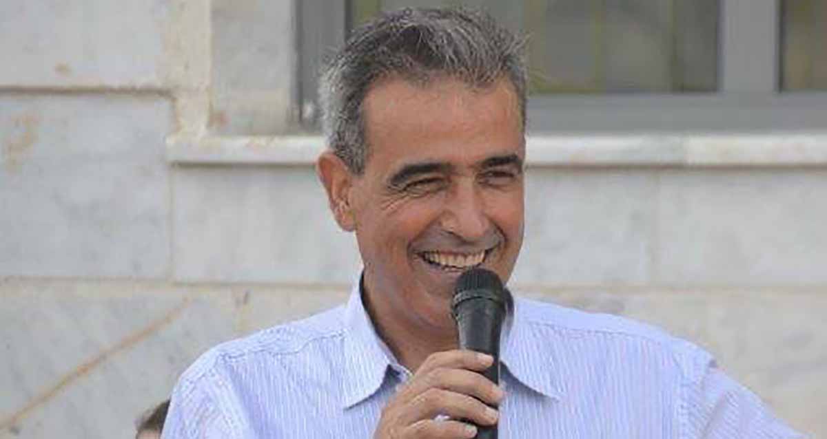 מאיר דהן תמונת פלג גוף עליון עם מיקרופון בידו.