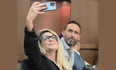 סיון שמרי דהן מצלמת עם טלפון נייד סלפי את עצמה ואת גיא קלנר ישובים על כסאות חברי המועצה ברמת השרון