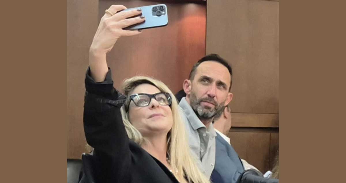 סיון שמרי דהן מצלמת עם טלפון נייד סלפי את עצמה ואת גיא קלנר ישובים על כסאות חברי המועצה ברמת השרון