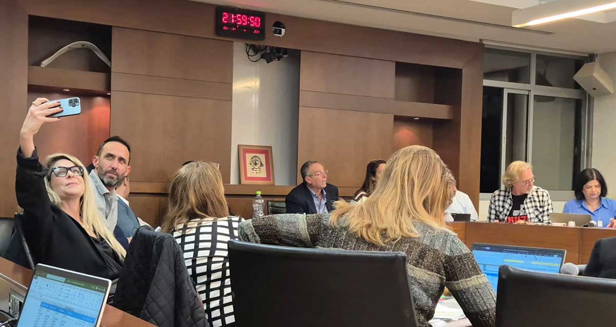 סיון שמרי דהן מצלמת עם טלפון נייד סלפי אותה ואת גיא קלנר בישיבת מועצת העיר רמת השרון. בתמונה נראים חברי מועצה נוספים וראש העיר איציק רוכברגר