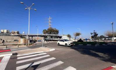 תחנת הרכבת הרצליה. בצד ימין כיכר ומכונית לבנה. בצד שמאל מעבר חצייה להולכי רגל של שני מסלולים. ברקע גשרים להולכי רגל