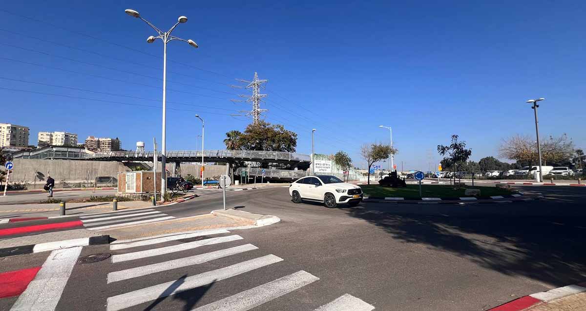 תחנת הרכבת הרצליה. בצד ימין כיכר ומכונית לבנה. בצד שמאל מעבר חצייה להולכי רגל של שני מסלולים. ברקע גשרים להולכי רגל