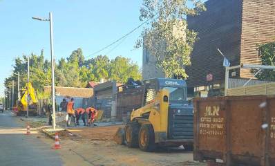 עבודות פיתוח ברחוב כצנלסון בכפר סבא. על המדרכה חונה טרקטור ולידו מיכל גדול לאיסוף פסולת הנייה. שלושה פועלים מרצפים את המדרכה.