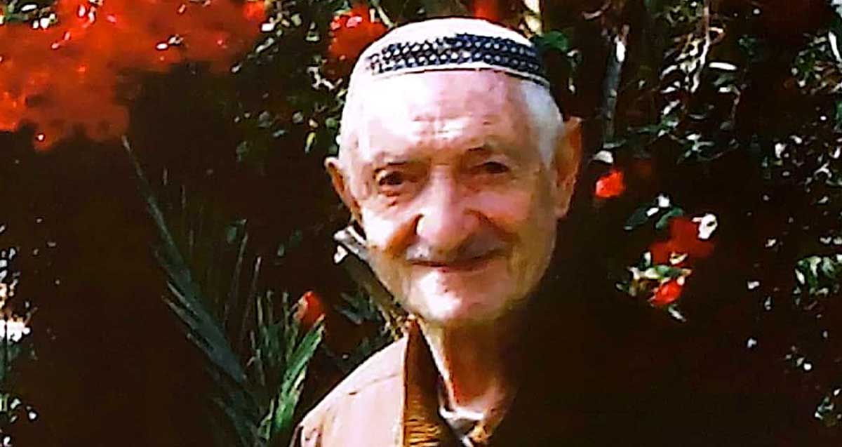 יוסף פרדו חובש כיפה על רקע גינת פרחים. תמונת פנים ישנה