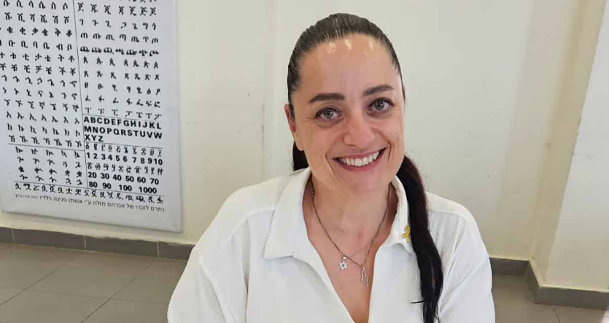 עו"ד עדי לוי סקופ. צילום פלג גוף עליון. על הקיר מאחוריה פלקט גדול עם סימנים.