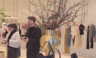 ביג פאשן גלילות - הכנות אחרונות לפתיחה. תמונה של חנות בגדים התלויים על מתלה בחנות. שני אנשים עם טלפונים ביד בתוך החנות.