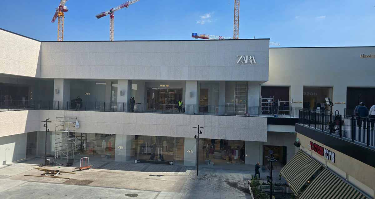 ביג פאשן גלילות - הכנות אחרונות לפתיחה. תמונה של בניין של שתי קומות עם חנויות ועל הקיר החיצוני שלט באנגלית: ZARA