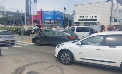 הכביש הפנימי שמוביל לביג פאשן גלילות. מכוניות פרטיות בכביש. ברקע מימין מבנה לבן עם הכיתוב: פיצה הר סיני. במרכז מבנה צבוע בכחול עם כיתוב באנגלית: B-FRESH. לידו מבנה צבוע באדום עם הכיתוב: אהרוניס. אופנועים חונים במדרכה לפני החנויות.