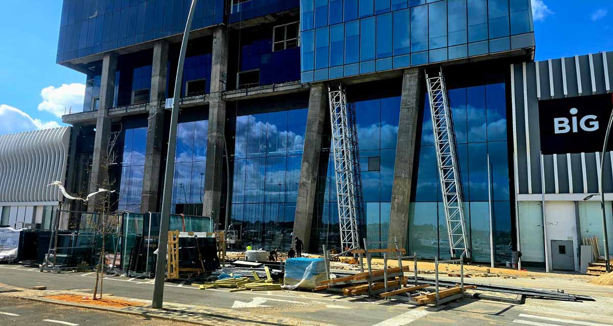 מתחם ביג גלילות רגע לפני הפתיחה. שתי הקומות התחתונות בעבודות חיפוי של מסגרות זכוכית כחולה. חומרי בנייה על הכביש לפני המבנה.
