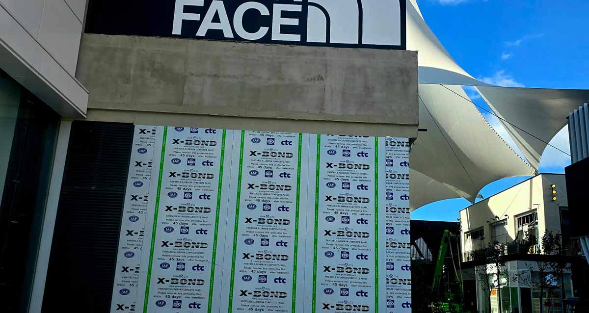 מתחם ביג גלילות רגע לפני הפתיחה. תמונה של חנות בשם: FACE, ובחזית על קיר הזכוכית מדבקות להגנה על הזכוכית, עם הכיתוב: X-BOND
