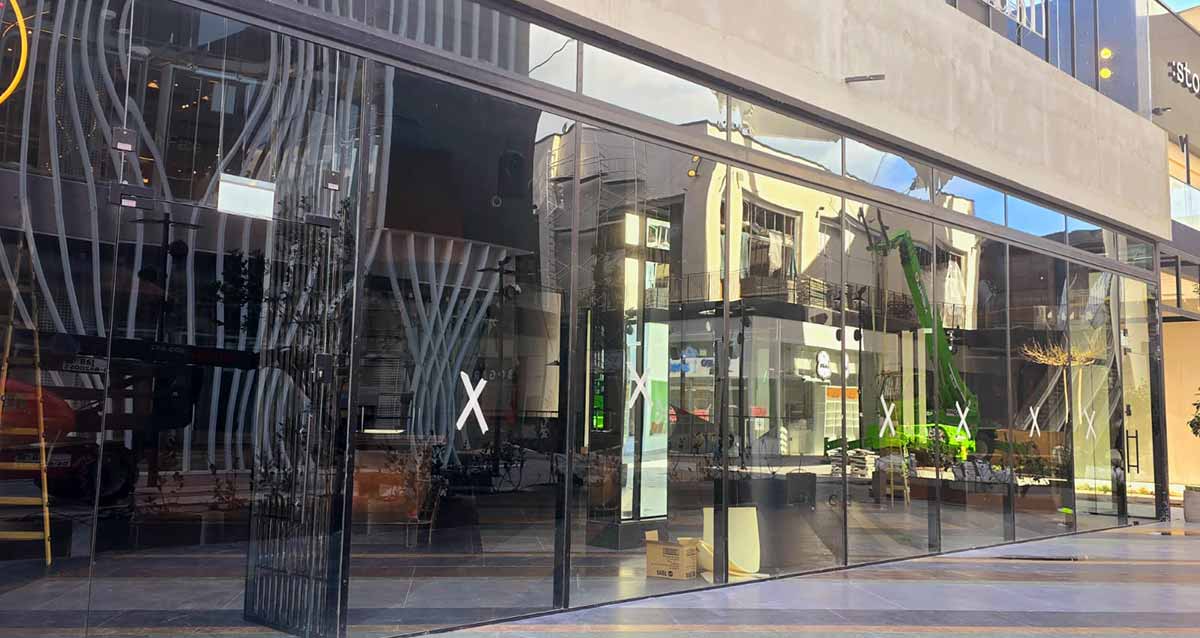 מתחם ביג גלילות רגע לפני הפתיחה. שורה של חנויות עם קירות זכוכית ומדבקות X על הזכוכית.