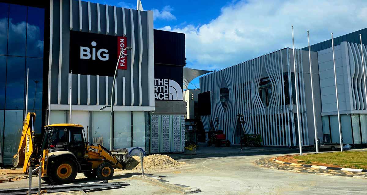 מתחם ביג גלילות רגע לפני הפתיחה. צילום של הקניון מבחוץ. טרקטור לפני המבנה. על הקיר הכיתוב באנגלית: BIG FASHION