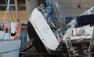 הסירה שקרסה במרינה בהרצליה. הסירה מונחת על המשטח ועל צידה. שמה באנגלית: ROCA LONDON. לפניה עומד אדם. מימין ומשמאל סירות.