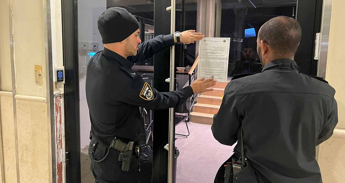 קזינו לא חוקי בהרצליה פיתוח. שני שוטרים מדביקים צו סגירה בפתח הקזינו.