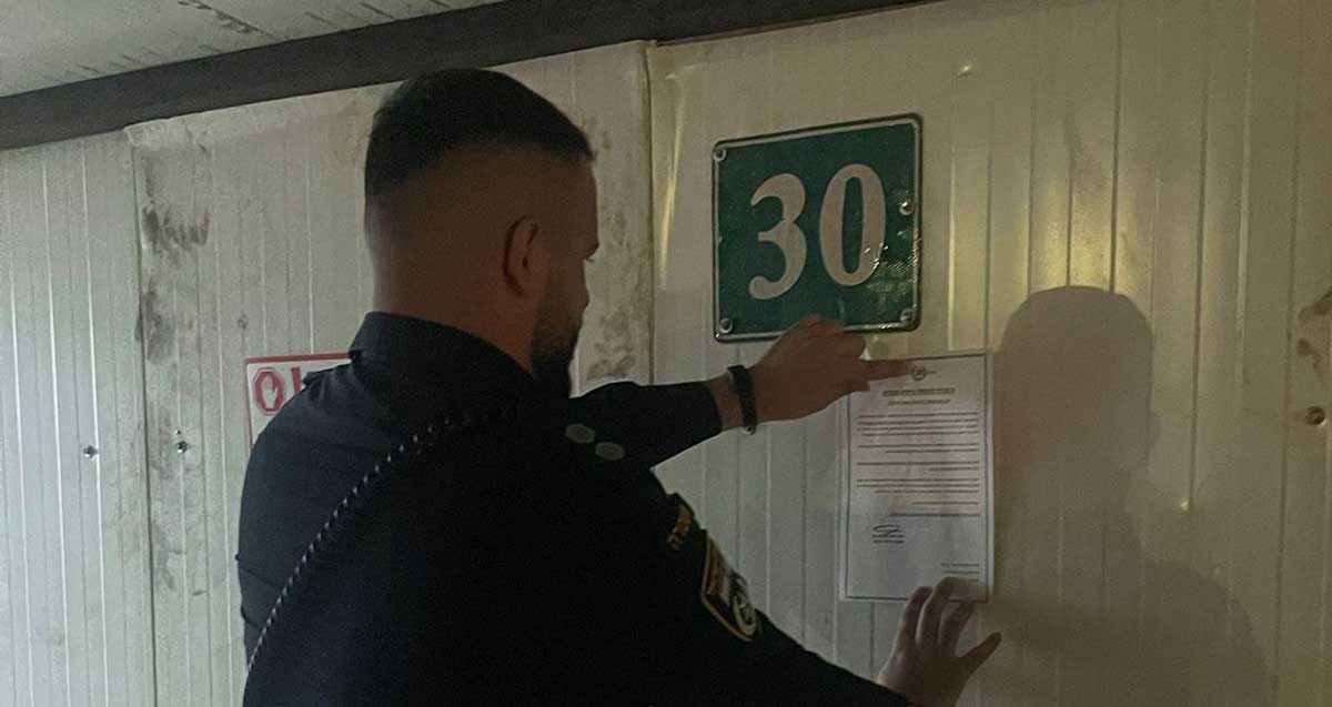 שוטר מדביק צו סגירה זמנית על גדר של אתר בנייה בכפר סבא עקב תפיסת עובדים שוהים בלתי חוקיים