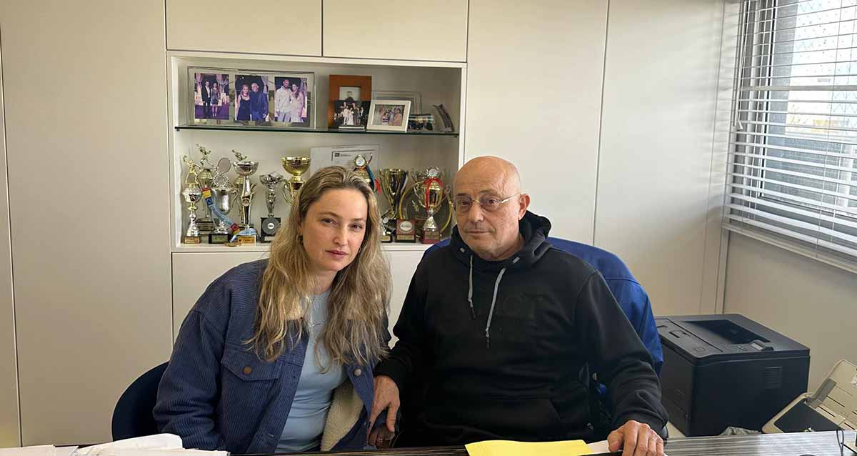 רואי החשבון יפתח גסר ושי גסר יושבים במשרד ליד שולחן. מימין מדפסת. מאחוריהם בתוך הקיר שקע עם גביעים ותמונות.