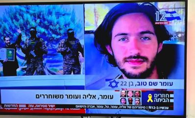 עומר שם טוב, מימין, על הבמה בעזה - מחויך ומנופף בידיו. צילום מסך מתוך ערוץ 12