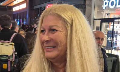 אורלי בר. תמונה של הפנים, עם שיער בלונדיני, על רקע חנות של POLO. מאחוריה אנשים.