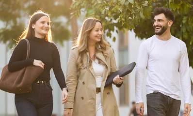 שתי סטודנטיות וסטודנט לתואר שני הולכים בדשא של רייכמן