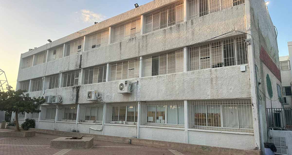 בית הספר היסודי גולן במערב רמת השרון. מבנה של שלוש קומות עם חלונות גדולים ותריסים. בקומה התחתונה סורגים בחלונות. רחבה מרוצפת לפני הבניין ושני עציצים בנויים מבטון ובאחד מהם עץ.