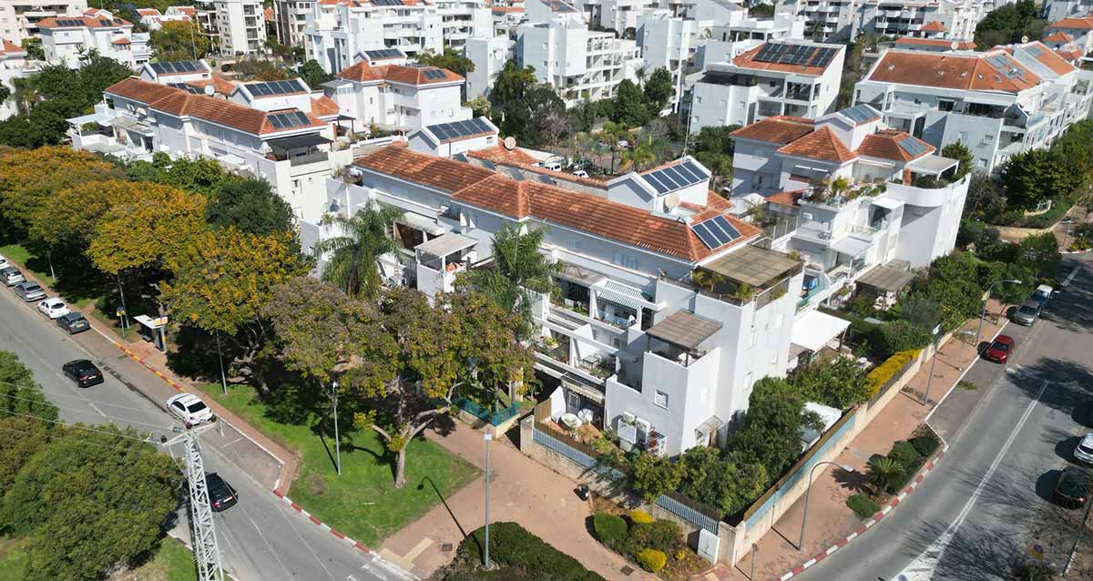 שדרוג שכונת 2004 ברעננה. צילום מגבוה של השכונה בהצטלבות של שני רחובות. השכונה של בתים בני 4 קומות עם גגות רעפים. ברקע בניינים גבוהים.