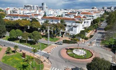 שדרוג שכונת 2004 ברעננה. צילום מגבוה של השכונה בהצטלבות של שני רחובות. כיכר עגולה עם ירק ועמוגדים בהצטלבות הרחובות. השכונה של בתים בני 4 קומות עם גגות רעפים. ברקע בניינים גבוהים. רחוב אחד הוא עם שני מסלולים ושדרה באמצע.