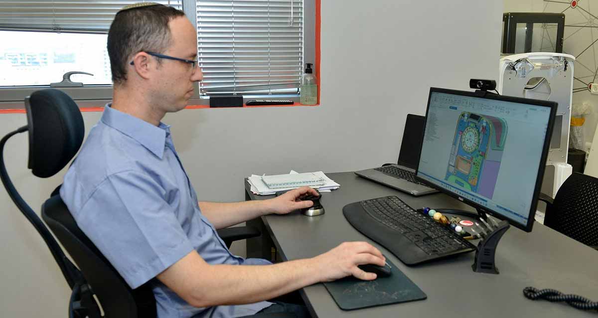 צוות גיאומטריקס רעננה. עובד החברה יושב ליד שולחן ובו מסך מחשב, מקלדת, עכבר בידו הימנית ומכשיר נוסף בידו השמאלית.