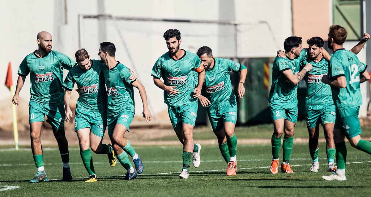 הפועל 1928 כפר סבא. השחקנים בתלבןשת ירוקה רצים בשורה על הדשא.