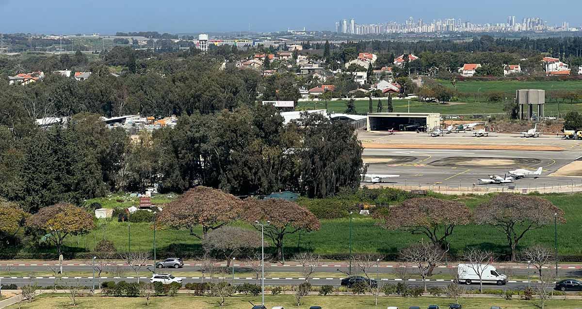 שכונת נחלת עדה בהרצליה. במרכז התמונה שדה התעופה של הרצליה ומעבר לו בתים חד קומתיים של השכונה. ברקע בניינים גבוהים.