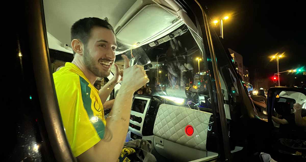 עומר שם טוב חזר להרצליה בתוך הרכב עם האגודל של שתי הידיים כלפי מעלה. עומר בחולצה צהובה של נבחרת ברזיל בכדורגל.