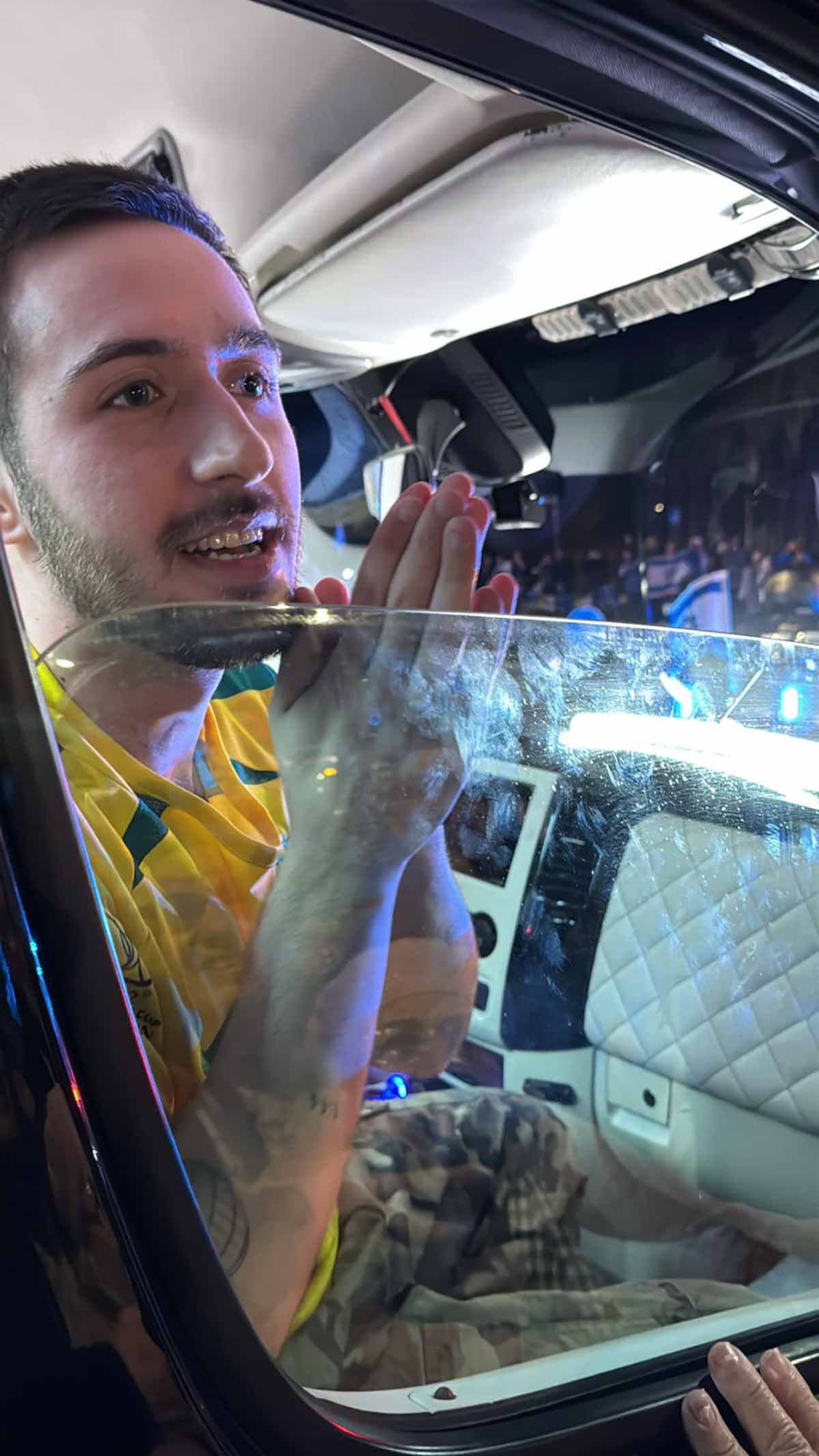 עומר שם טוב חזר להרצליה בתוך הרכב עם שתי כפות הידיים צמודות מודה לקהל. עומר בחולצה צהובה של נבחרת ברזיל בכדורגל.