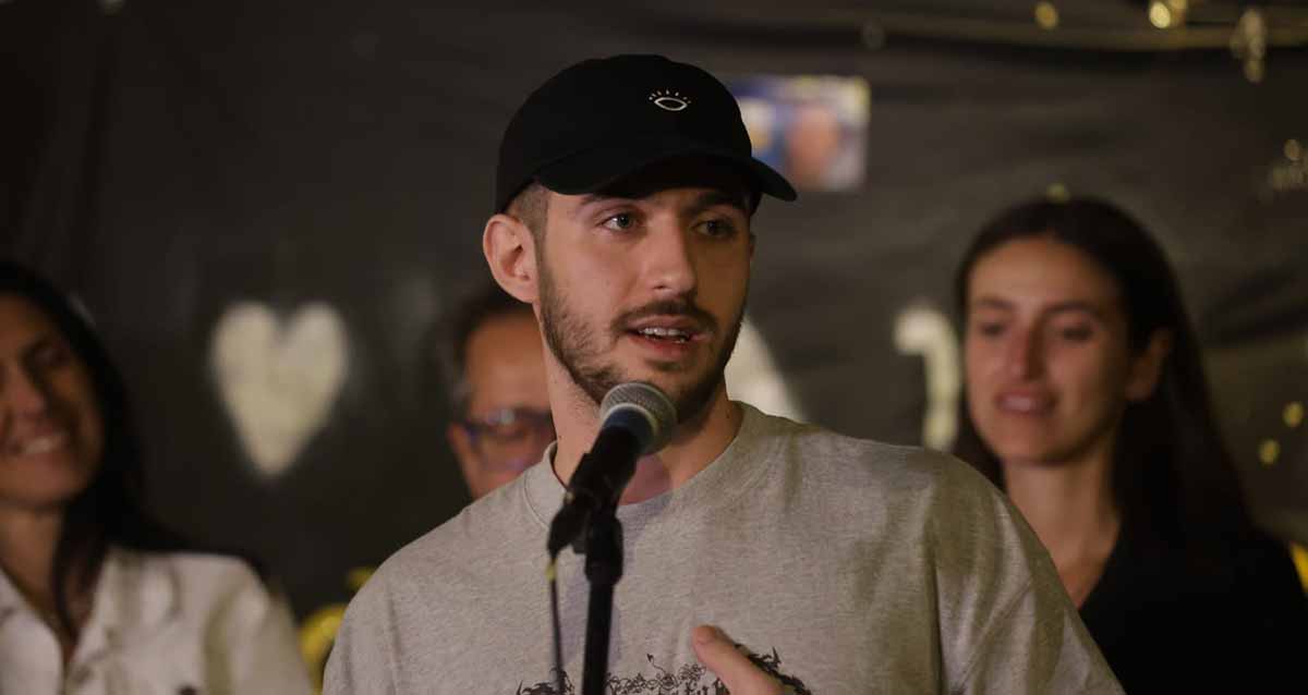 עומר שם טוב מדבר לקהל עם מיקרופון.