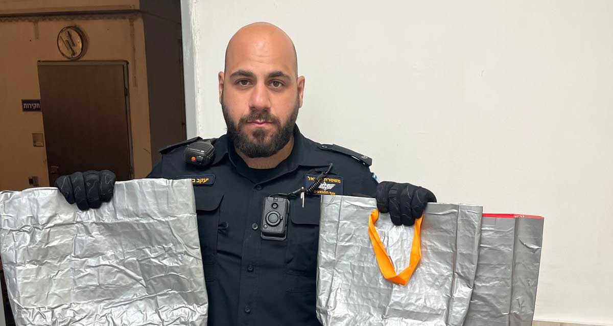 שוטר אוחז בשתי ידיו שקיות מנטרלות זמזמים