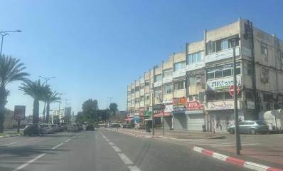 פינת הרחובות וייצמן והחרושת בכניסה לאזור התעשייה רעננה. בניין של ארבע קומות. חנויות ועסקים בקומת הקרקע, מיזוג, חשמל לרכב ועוד. משמאל רחוב וייצמן הרחב עם שדרת דקלים באמצע.
