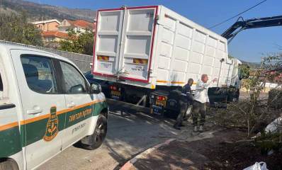 עובדי עיריית רמת השרון בקריית שמונה. משאית איסוף פסולת וטנדר של מחקת התברואה בעיריית רמת השרון, אוספים אשפה.שני עובדים עומדים ליד המשאית.