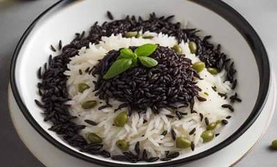 אורז בשני צבעים של שף שאול בן אדרת בקערה. האורז הלבן בתחתית והשחור במרכז ובהיקף הקערה. עלים ירוקים על האורז השחור וזיתים ירוקים מפוזרים.