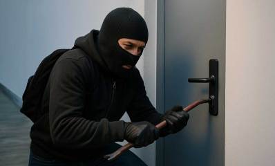 גנב פורץ לדירה עם לום, והוא עם כובע גרב ותרמיל על הגב.