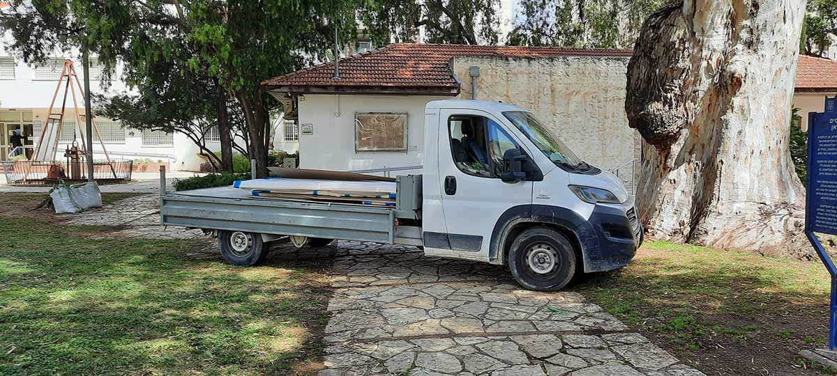 שיפוצים בלשכת ראש העיר כפר סבא. טנדר עם ציוד חונה לפני הבית החד קומתי עם גג רעפים.