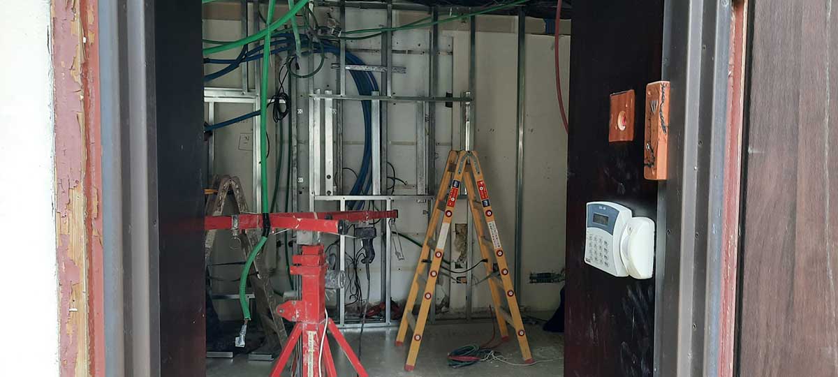 שיפוצים בלשכת ראש העיר כפר סבא. צילום בתוך הבניין. סולמות, צנרת מוטות אלומיניום, ושעון נוכחות בכניסה.