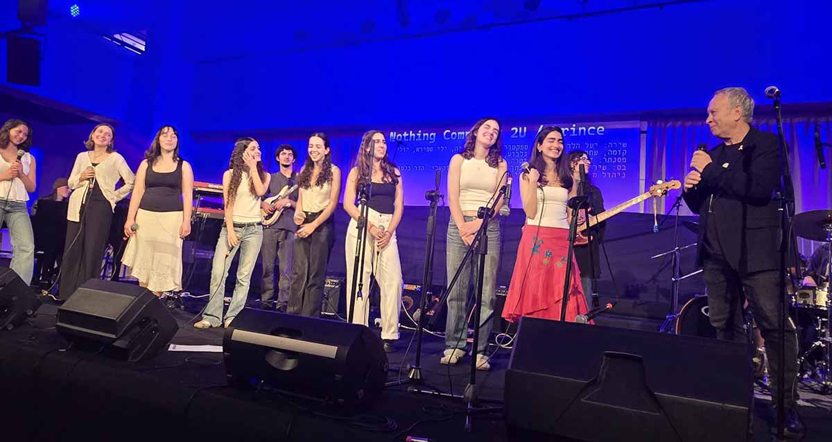 יואב קוטנר ותלמידי מגמת המוזיקה בתיכון אלון על במה עם מיקרופונים.