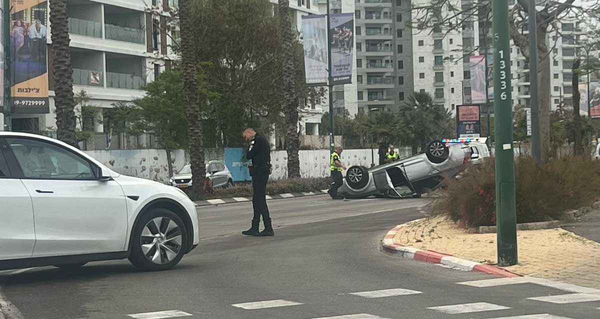 רכב התהפך ברחוב ז׳בוטינסקי בהרצליה, לידו שני שוטרים, ניידת ובוחן תנועה