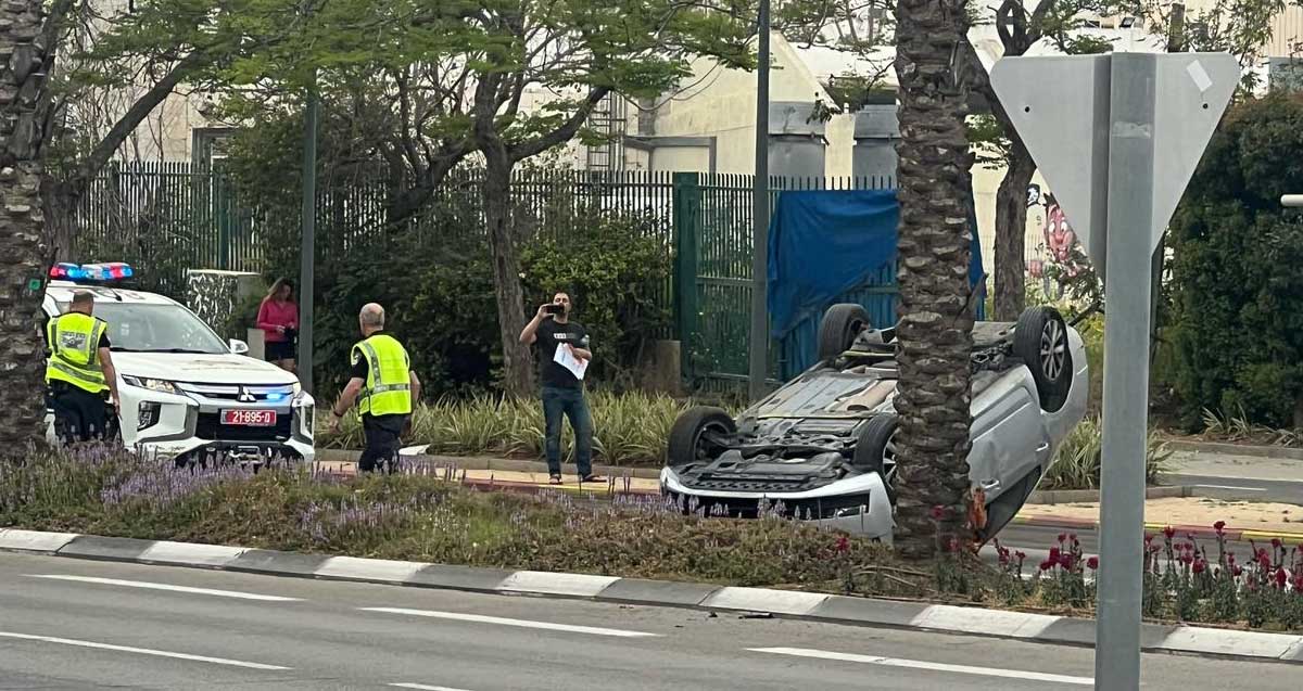 רכב התהפך ברחוב ז׳בוטינסקי בהרצליה, לידו שני שוטרים, ניידת ובוחן תנועה