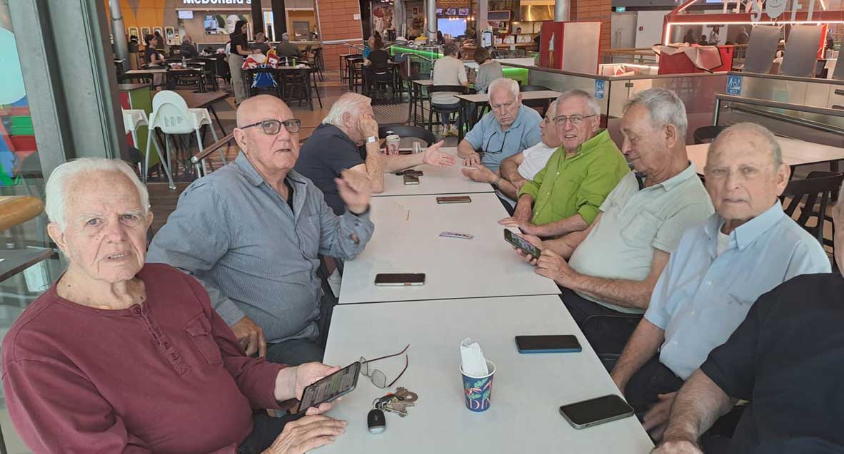 הפרלמנט של תושבי הרצליה במתחם הפאסט פוד של קניון שבעת הכוכבים יושבים סביב שלושה שולחנות המחוברים בטור. על השולחן טלפונים.