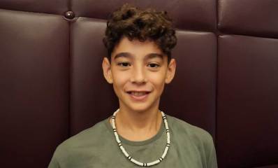 רום וילדר ז"ל, בחולצה ירוקה ושרשרת לבנה עם פסים שחורים סביב צווארו.